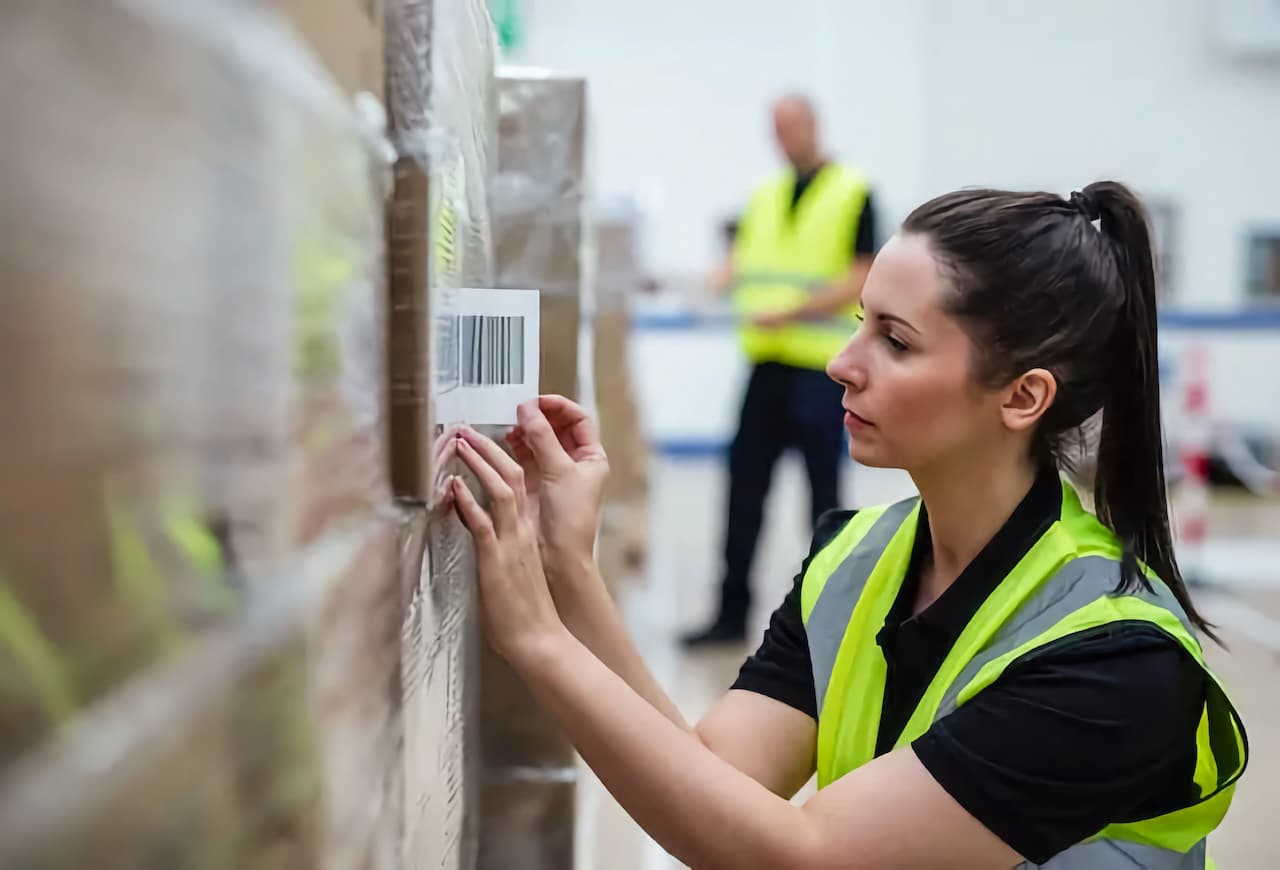 Mujer etiquetando cajas en almacen